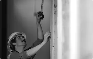 a Green Hammer employee with a hard hat taking a measurement with a tape measure