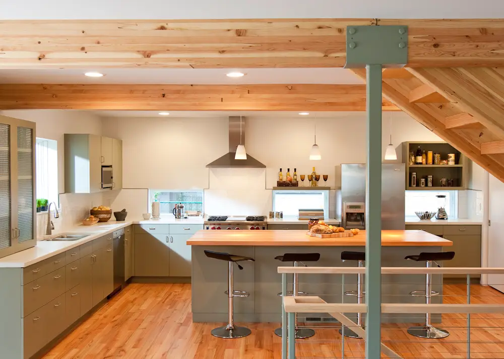 Overview of the kitchen with a central island surrounded by sage green cabinet with a crisp white quartz countertop.