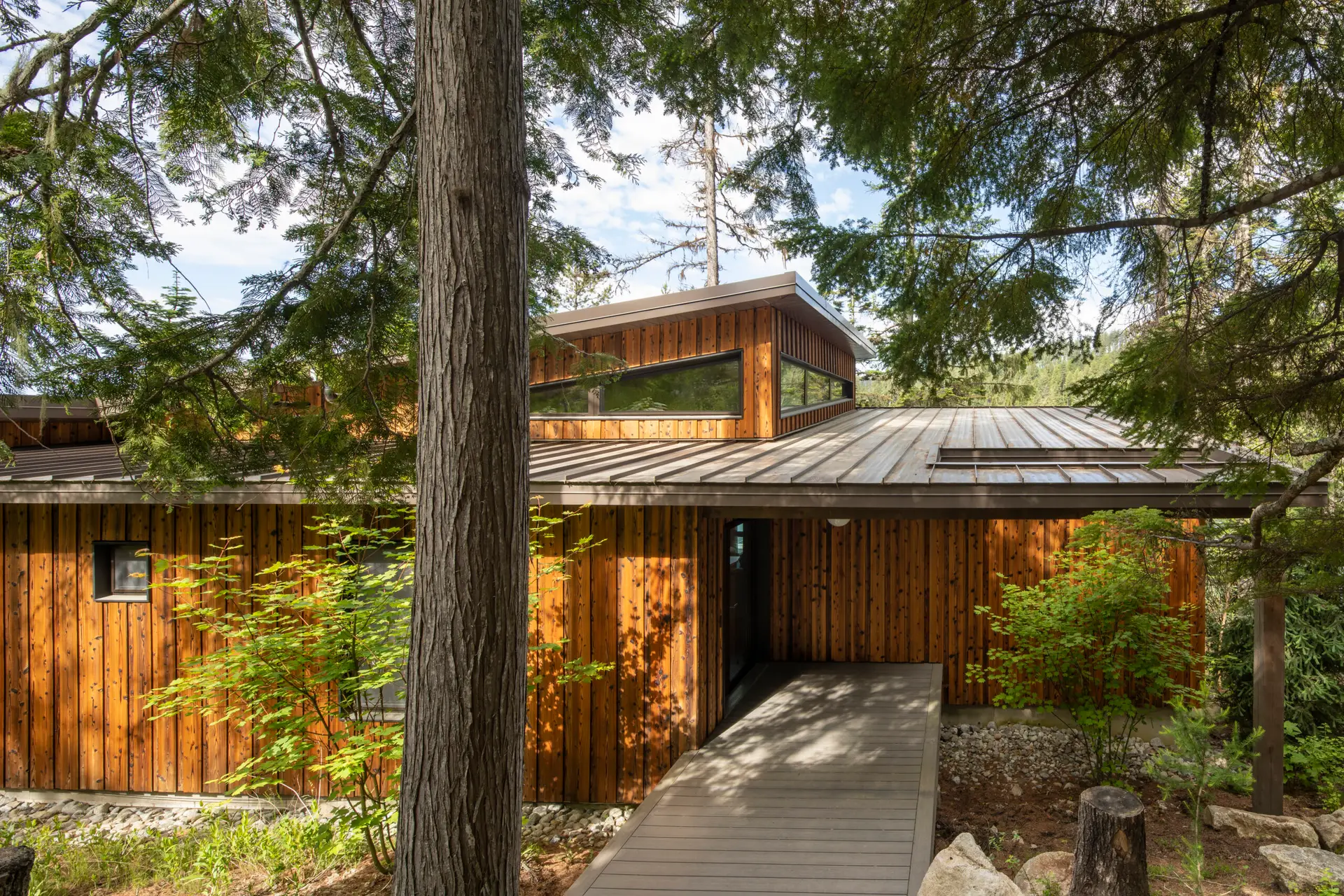 Priest Lake Cabin viewed from the exterior entry. Beautiful vertical wood siding and low sloped roofs can be experienced from this side.