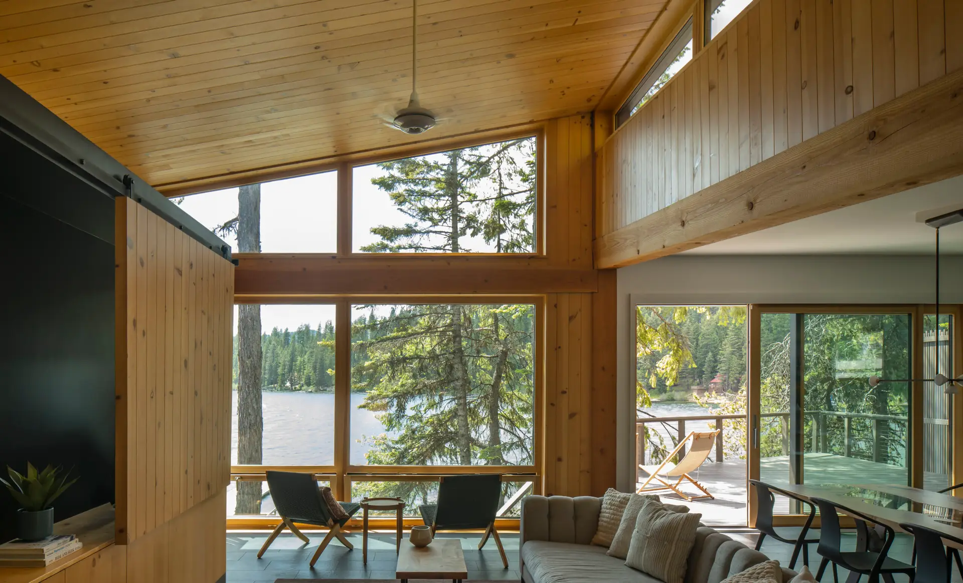 Priest Lake Cabin living room with a generous window wall with views to the lake and a high clerestory window to the upper right of the frame. The dining room is to the right in this image.