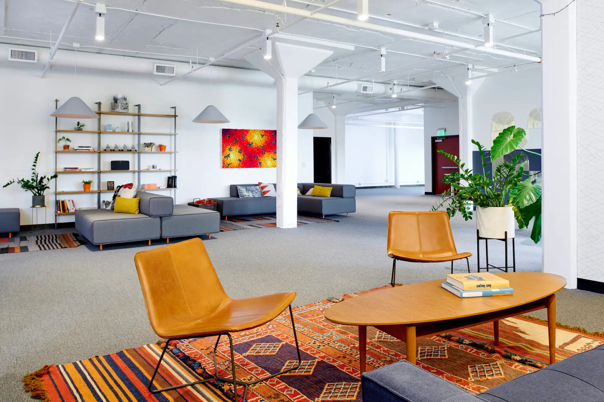 Communal lounge space in the Thinkshout offices featuring several seating options, a coffee table, and plants scattered about.