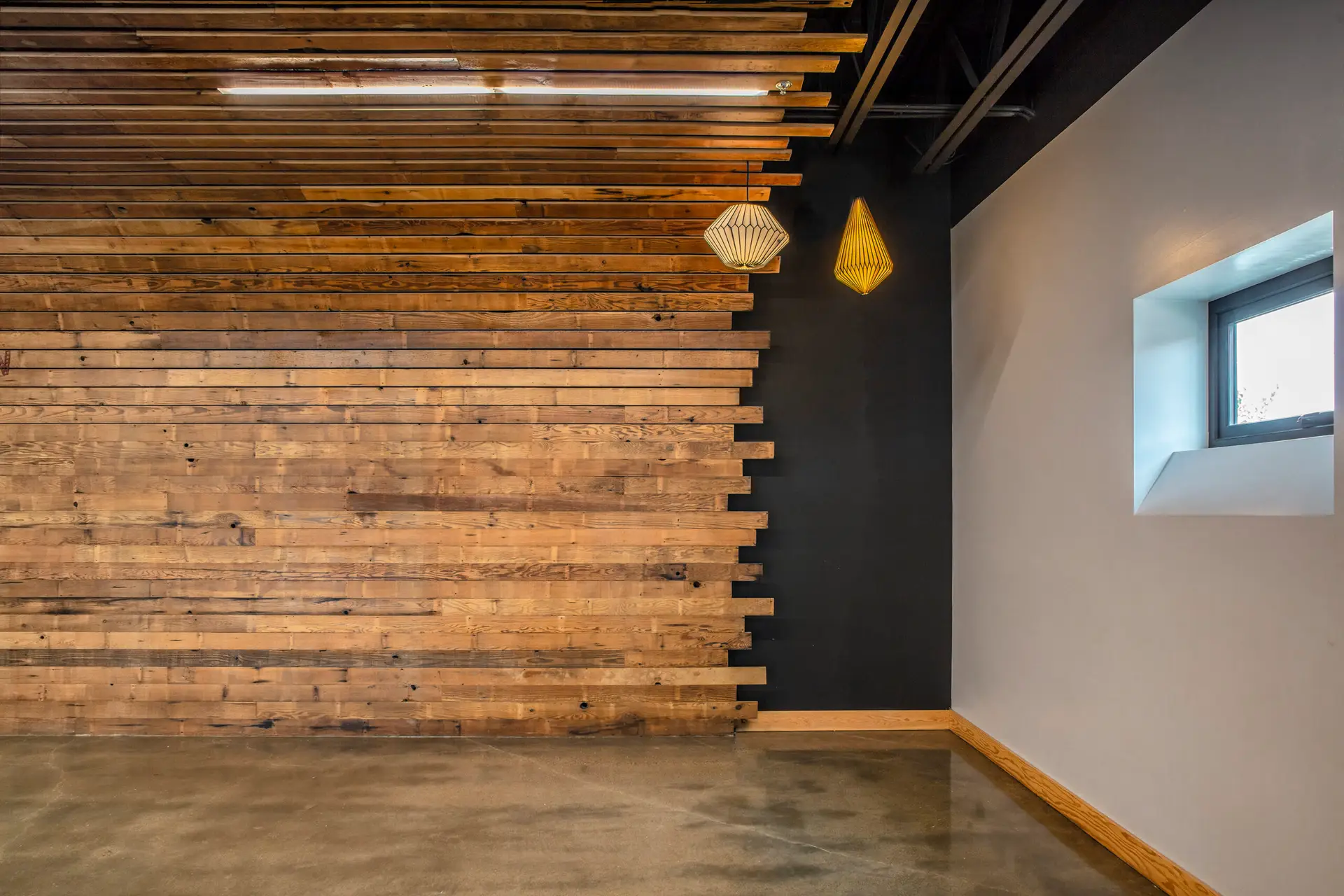 Intricate wood paneling at The Breath Building which is reclaimed wood. The floor is concrete which supports the goal of maximizing durability of this commercial space.
