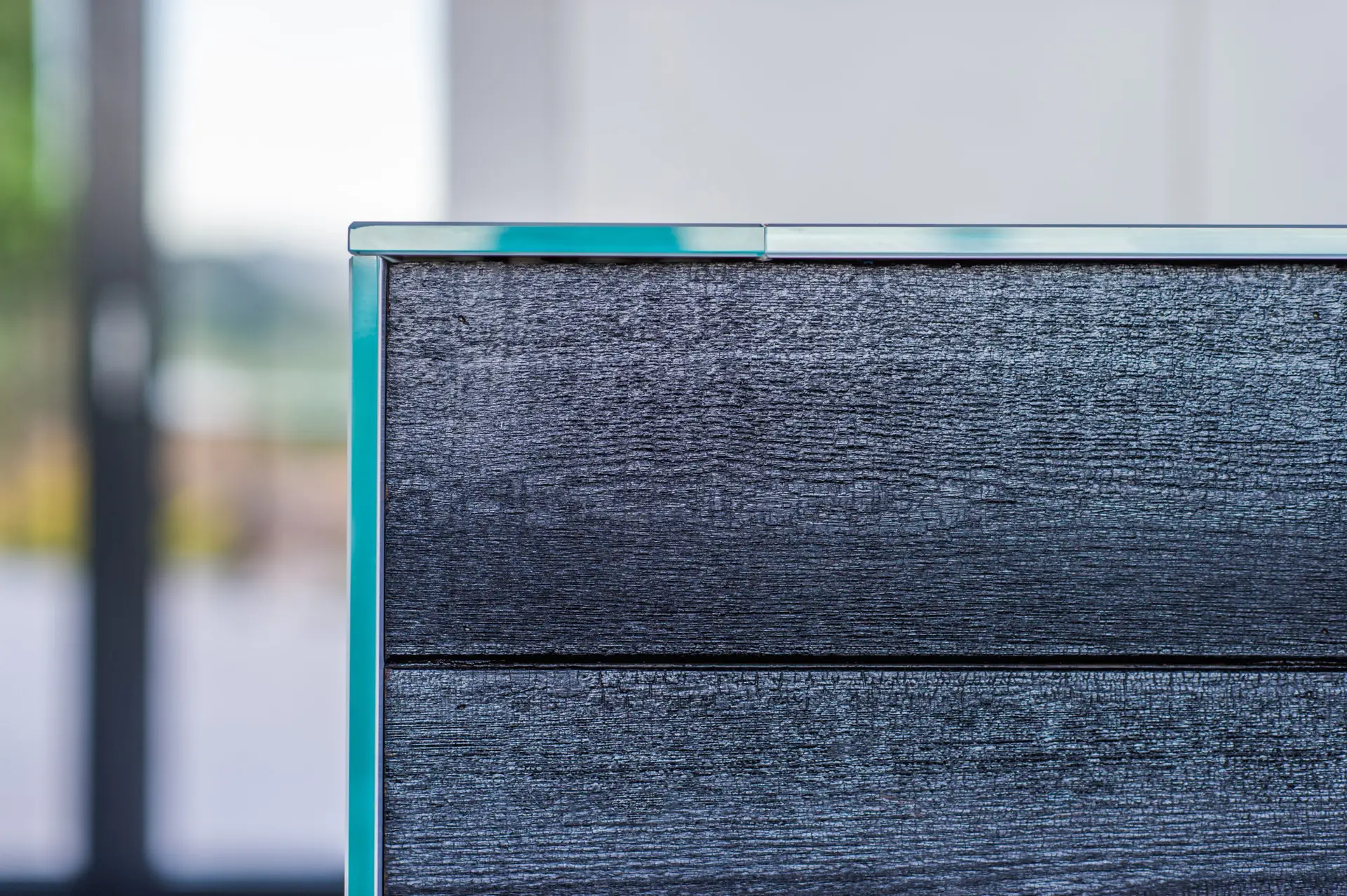 A close-up detali image of a corner joint with dark wood cladding and a blue metal cap