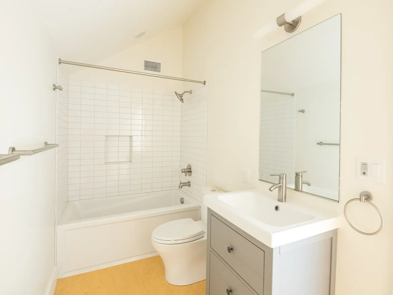 green grove upstairs bathroom which has a sloped ceiling with a shower in the back of the room and a toilet between the shower and vanity.