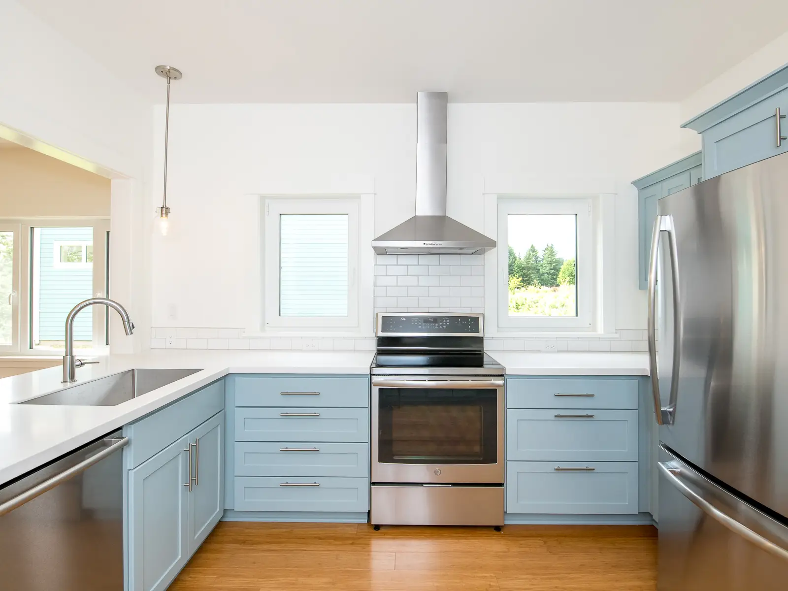 Green Grove CoHousing kitchen which features baby blue lower cabinets and bright white walls.