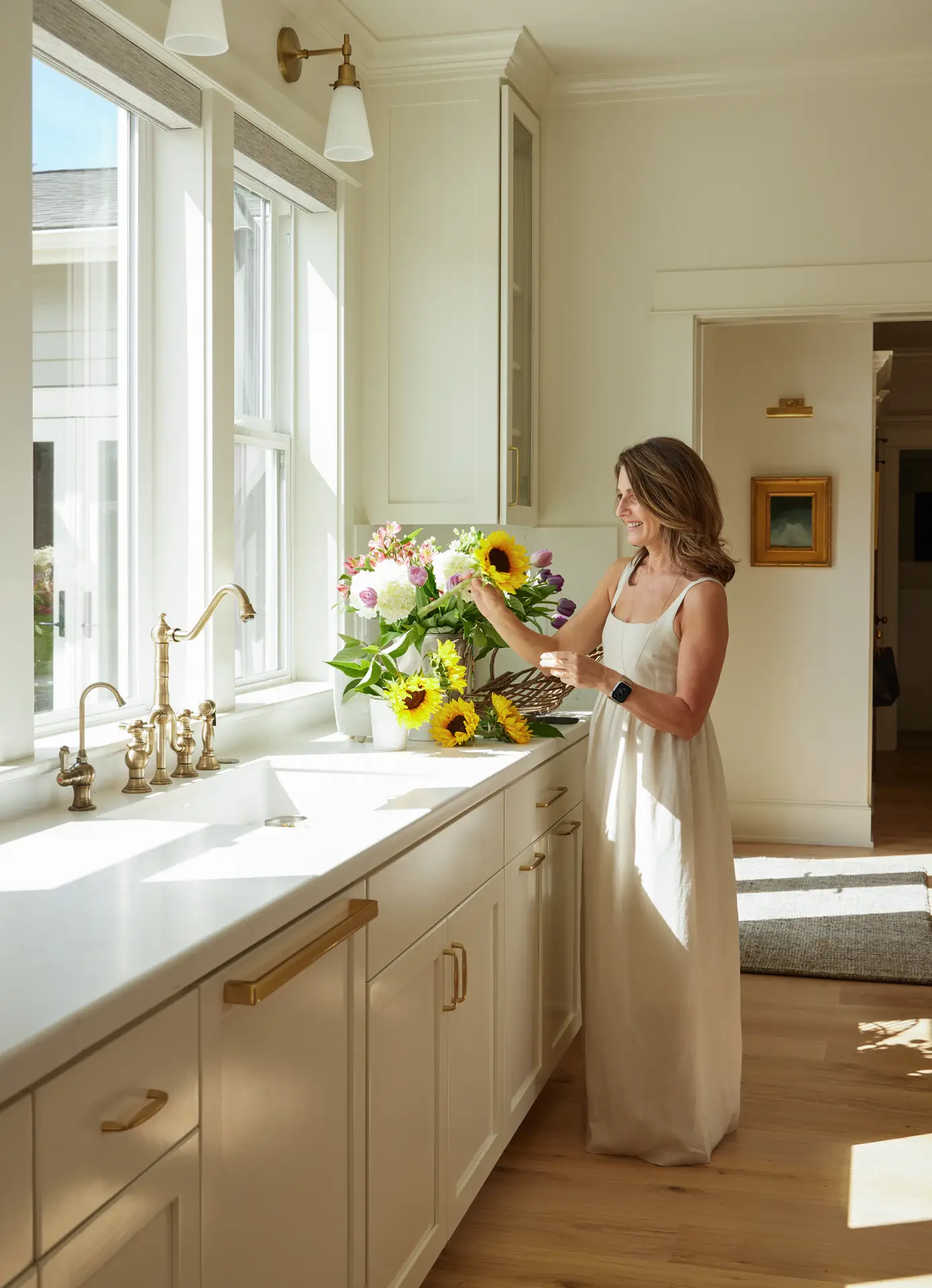 St. Paul Residence kitchen, featuring the kitchen sink and lots of light coming in through the window. A woman is also organizing a flower bouquet.