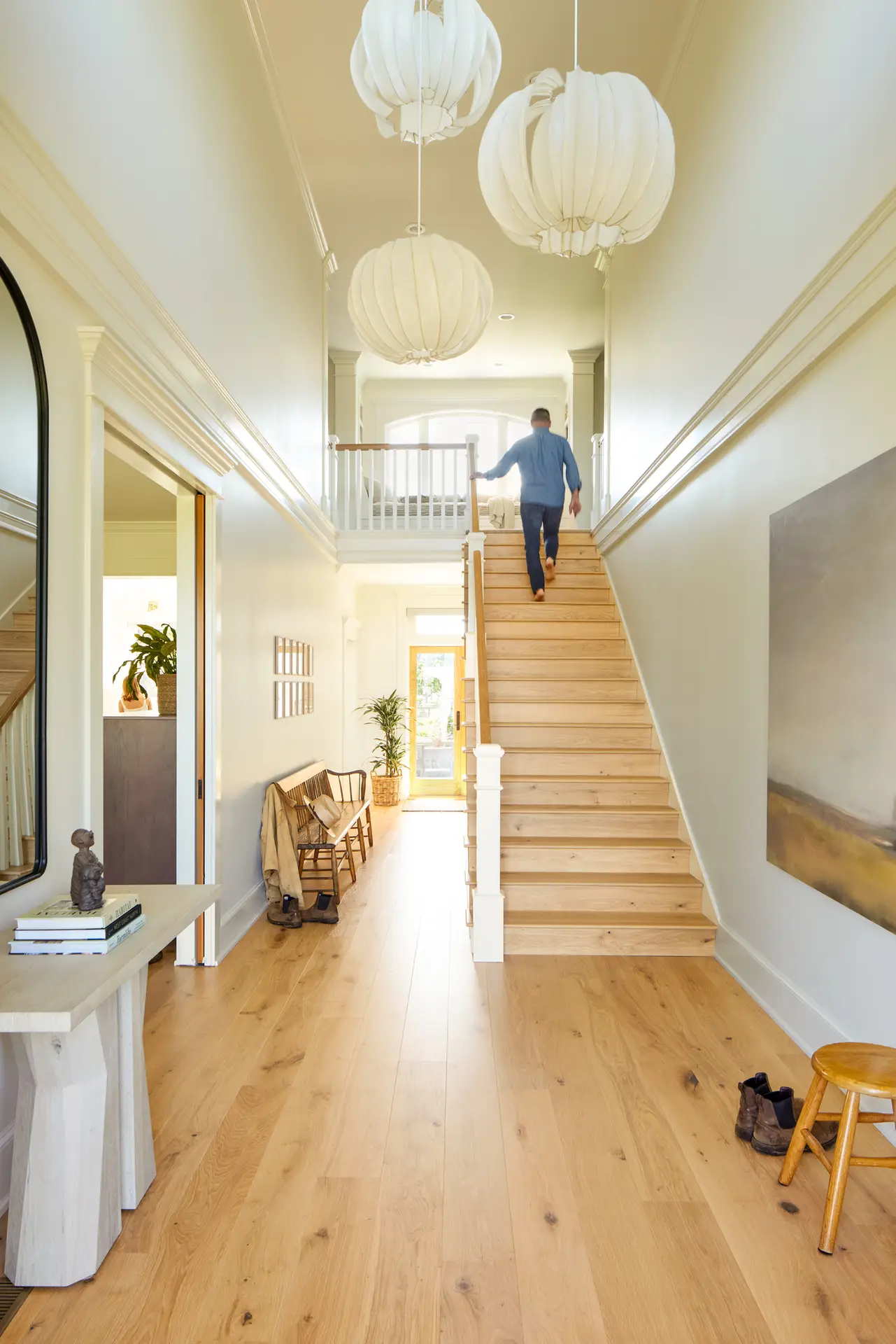 St. Paul Residence entry, featuring a generous and celebrated stair to the right with bright walls and light filled double height space. Warm wood floors bring us into the space.