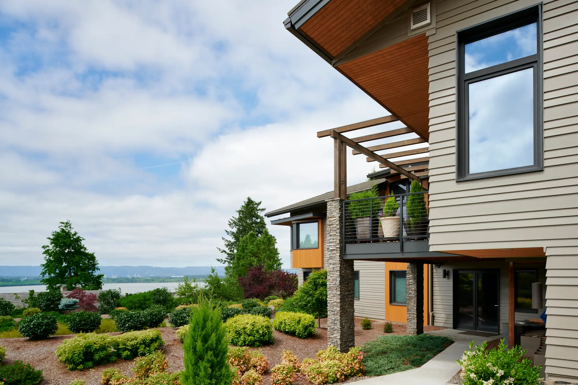 Vancouver Residence exterior and view of the valley. The homes features light grey exterior fiber cement siding combined with a natural wood soffit along with several thoughtfully placed wood accents.