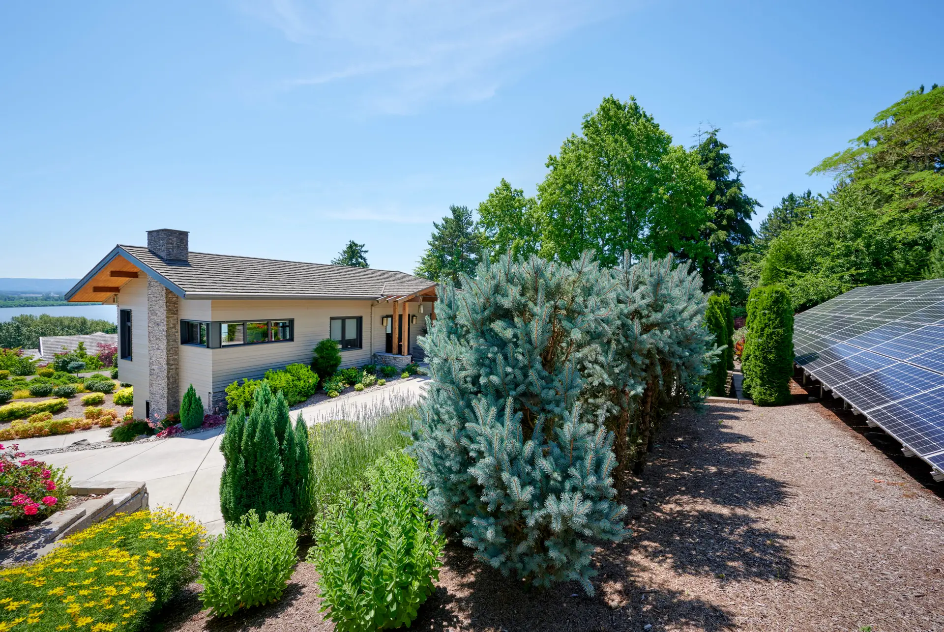 Vancouver Residence exterior, featuring a well landscaped sloping site with a PV array to the right and view of the home to the right