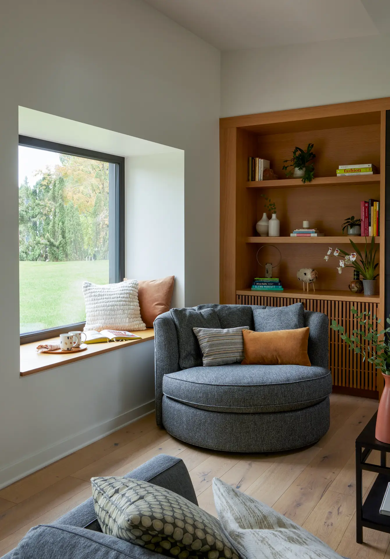 Sunset Residence window seat and built in bookshelf. There is also a round loveseat that anchors the corner and provides a soft edge to the space.