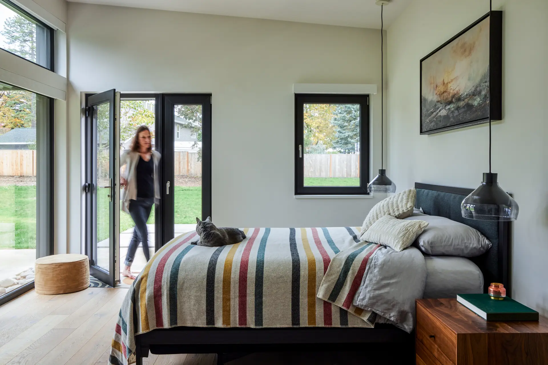 Sunset Residence bedroom, featuring a gently sloping ceiling out toward the exterior. The space is filled with natural light as several windows a placed along the exterior walls.