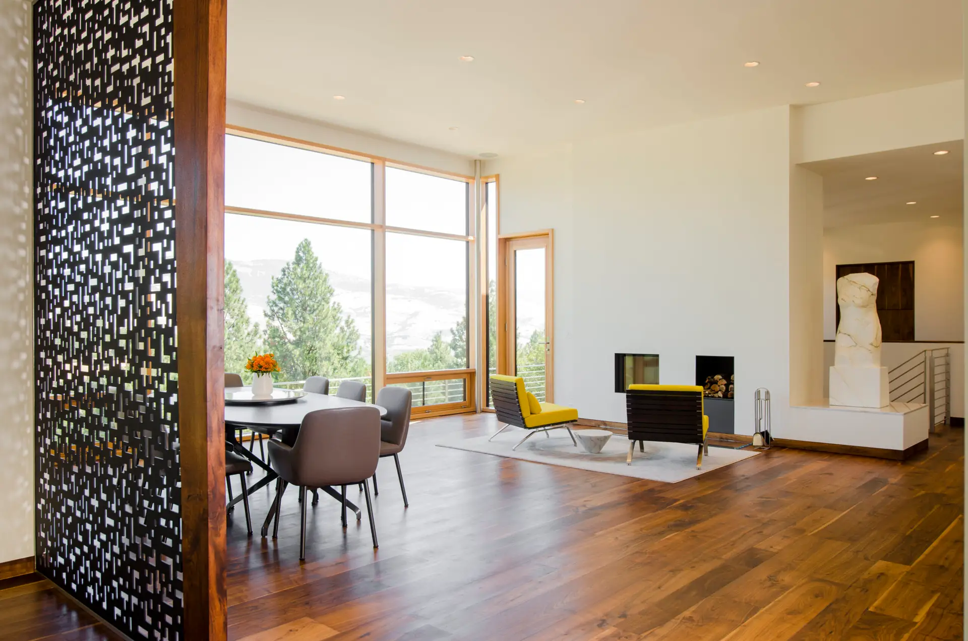 Fineline Custom Home open floor plan with wide-plank wood flooring, crisp white walls. The fireplace is the focal point with a niche for a large adjacent sculpture.