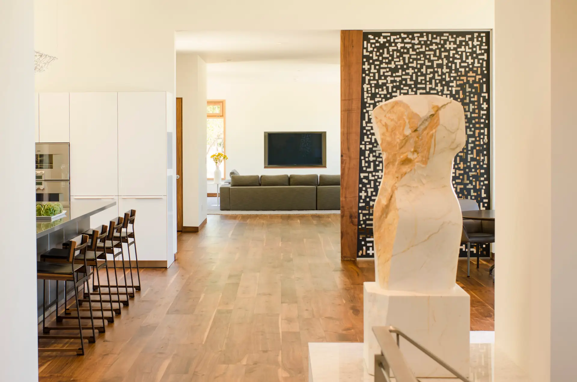 Fineline Custom Home features modern art throughout. On the right a white marble-style torso sculpture with a geometric room divider beyond made of laser cut metal.