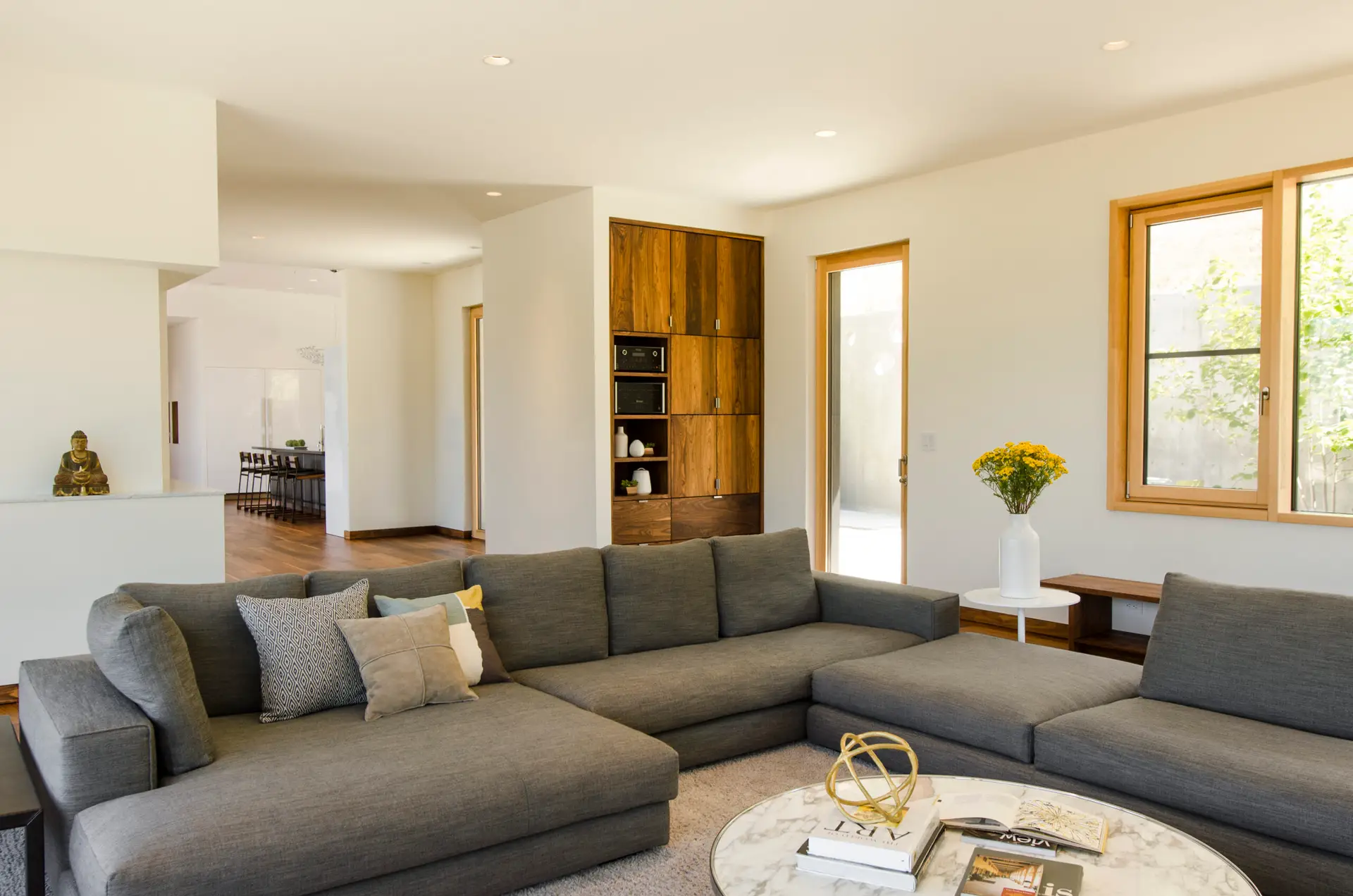 Fineline Custom Home family room with a central seating area with a dark grey U-shaped sectional sofa and round marble top coffew table.