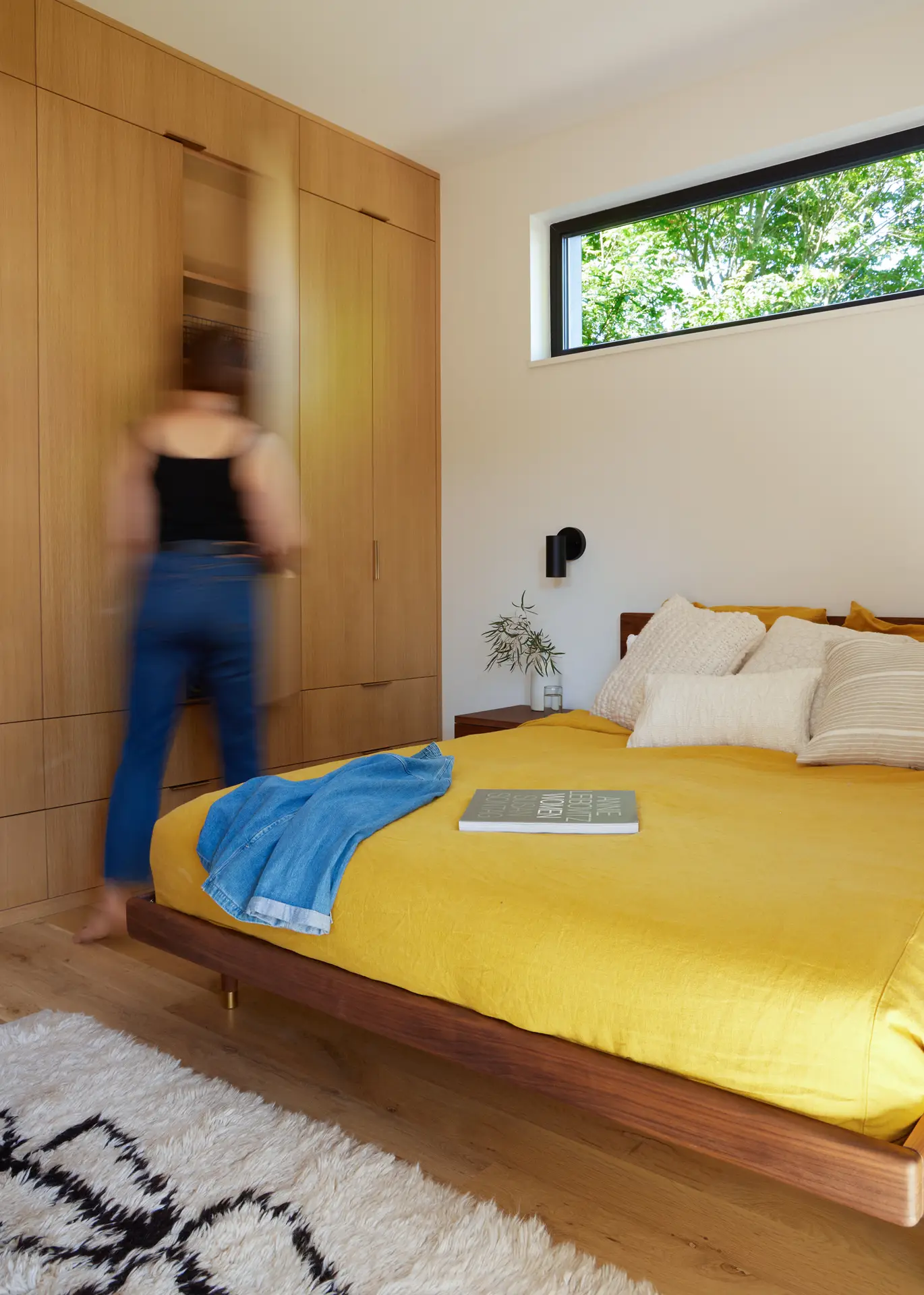 the Richmond residence bedroom, featuring a full height built in closet and a clerestory window behind the bed. The bed has a lovely yellow comforter on it.