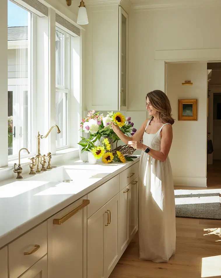 Green Hammer Client holding flowers in her kitchen by the window.