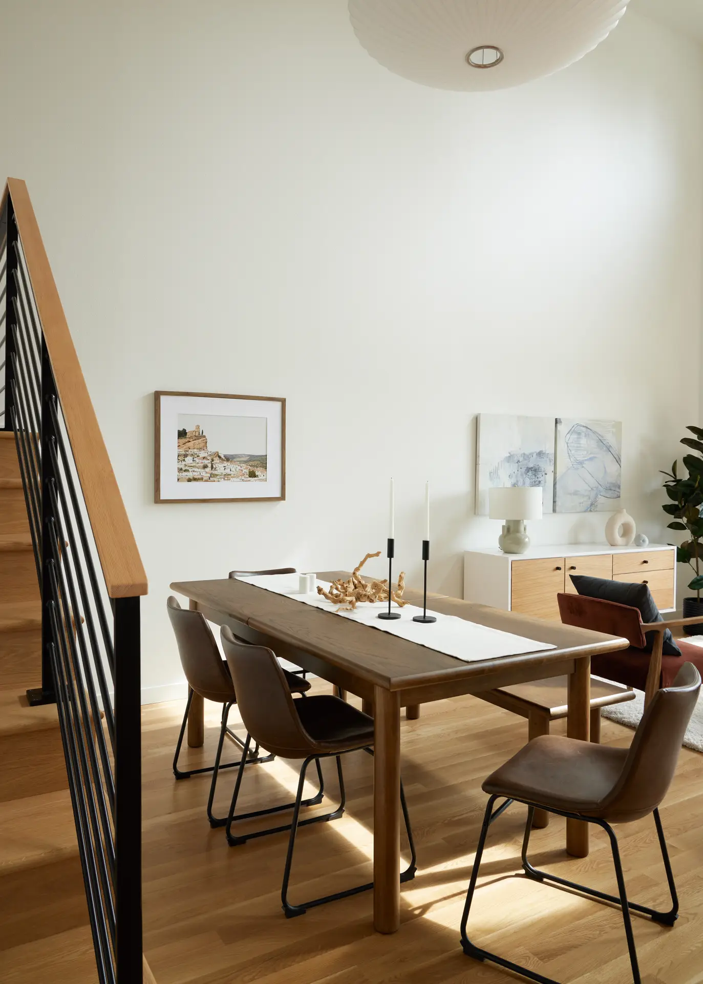 The dining room at Trillium Townhomes, featuring oak wood floors, a dark oak table with leather chairs. A Herman Miller Nelson Saucer Bubble Pendant above the table.