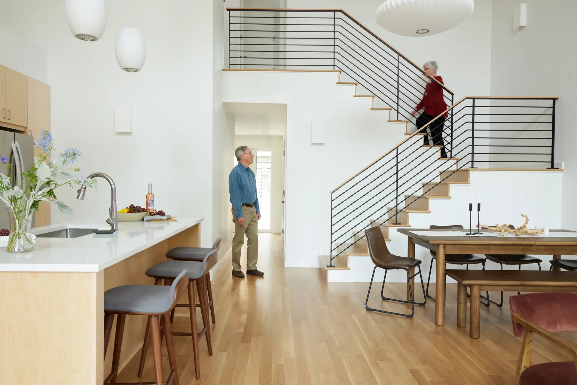 A soaring ceiling and crisp white walls, creating a voluminous and airy atmosphere. A large, iconic Nelson Bubble Lamp hangs prominently over the dining area.