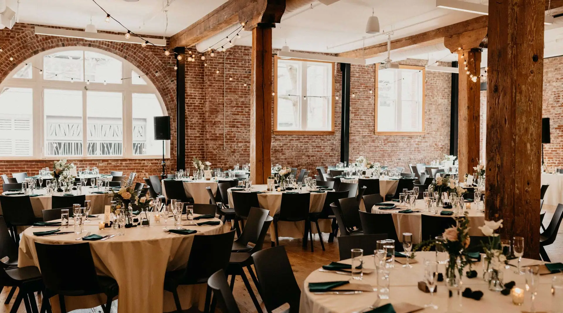 Irving street studio, showing the space setup for a wedding with round tables, table settings, and string lights