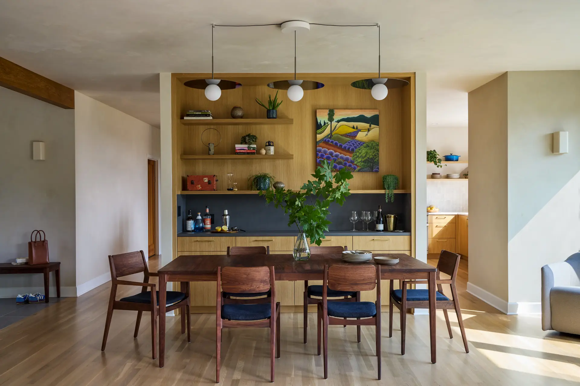 The dining room featuring a table custom-crafted by The Joinery, a Portland studio. Behind the table is a built-in oak bar and open shelving.