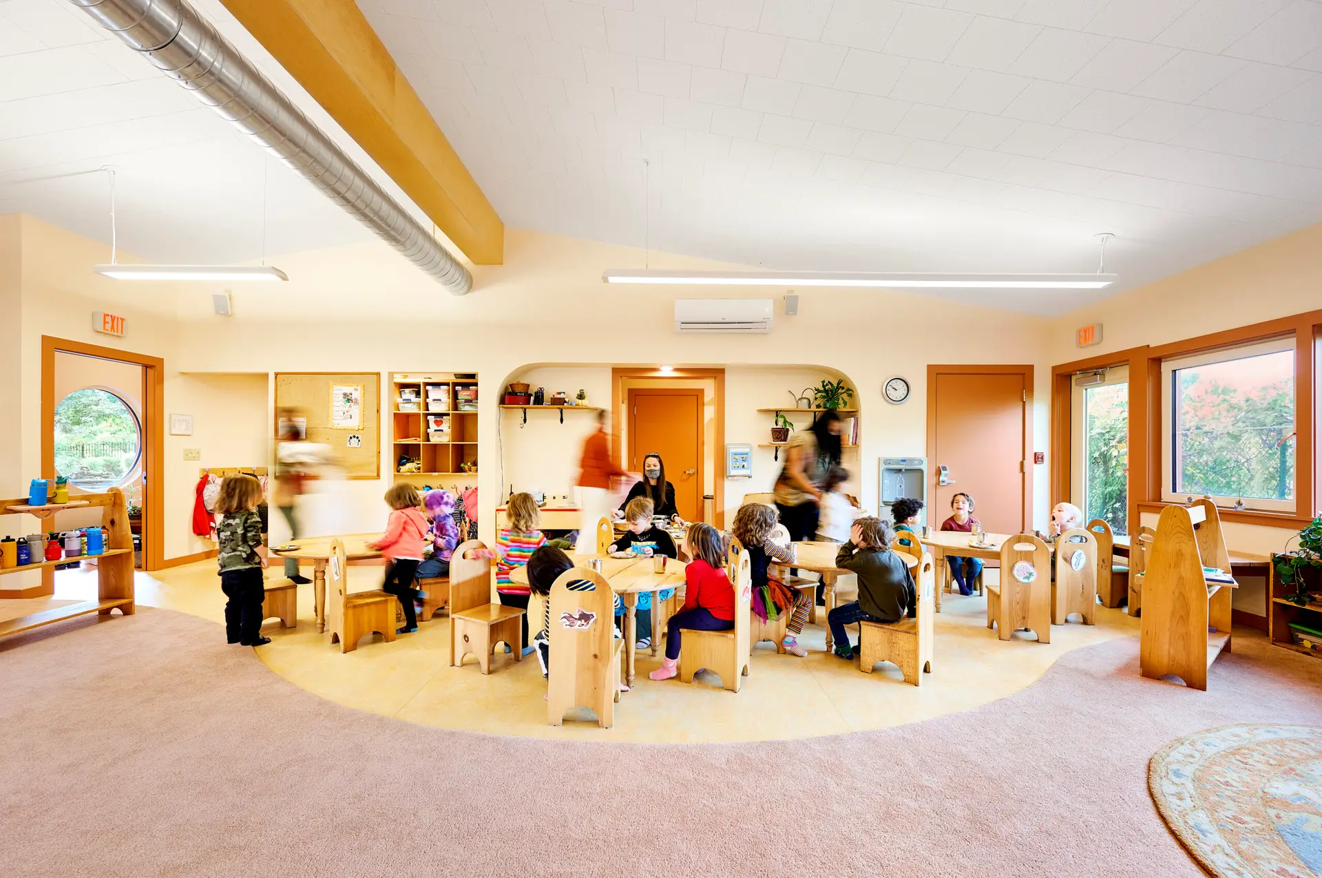 Children together learning in the New Day Classroom which has soft coloration paired with soft detailing such as a rounded window and rounded drywall corners.