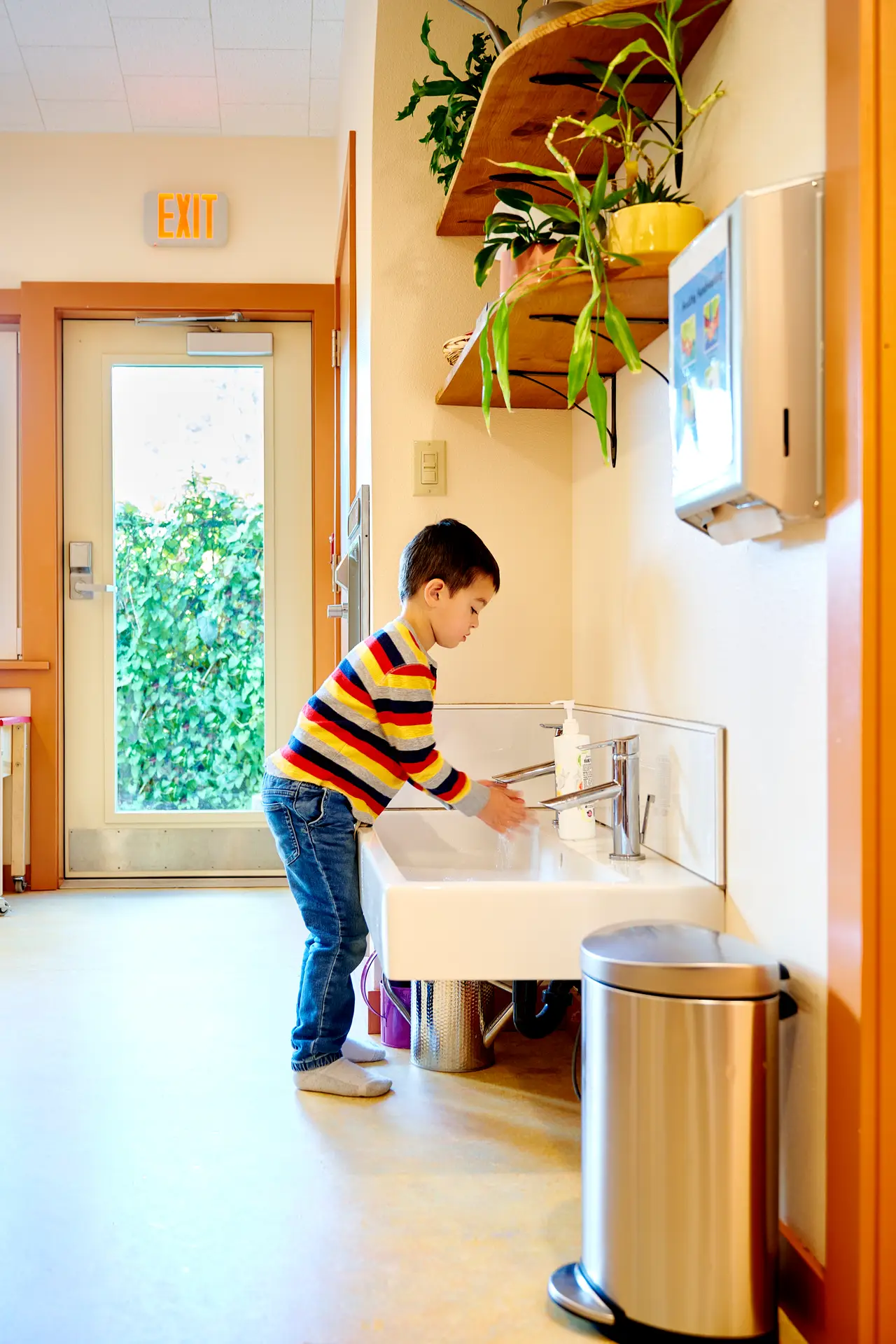 Child washing his hands in the sink.